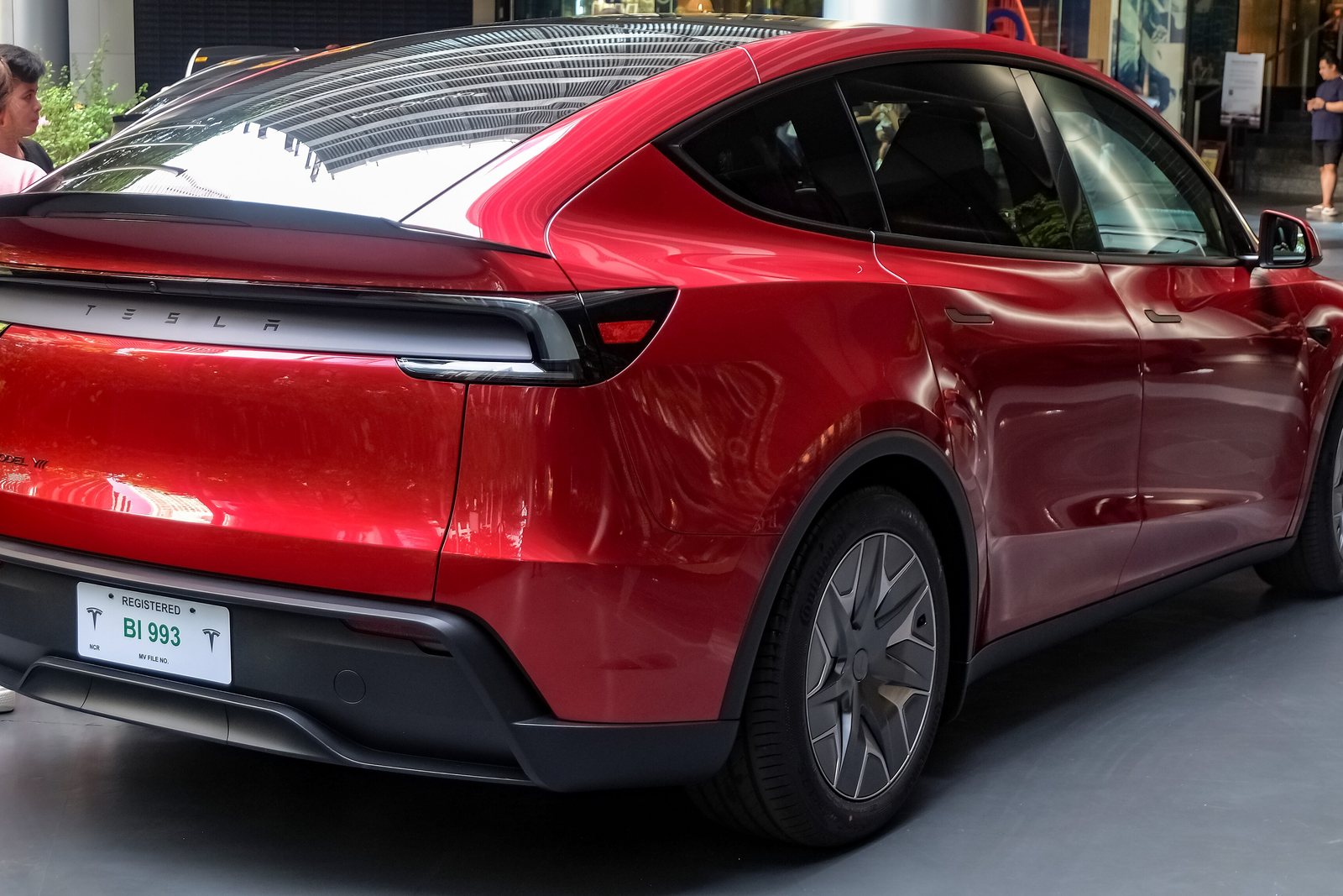 A red Tesla Model Y L six-seater parked on a street