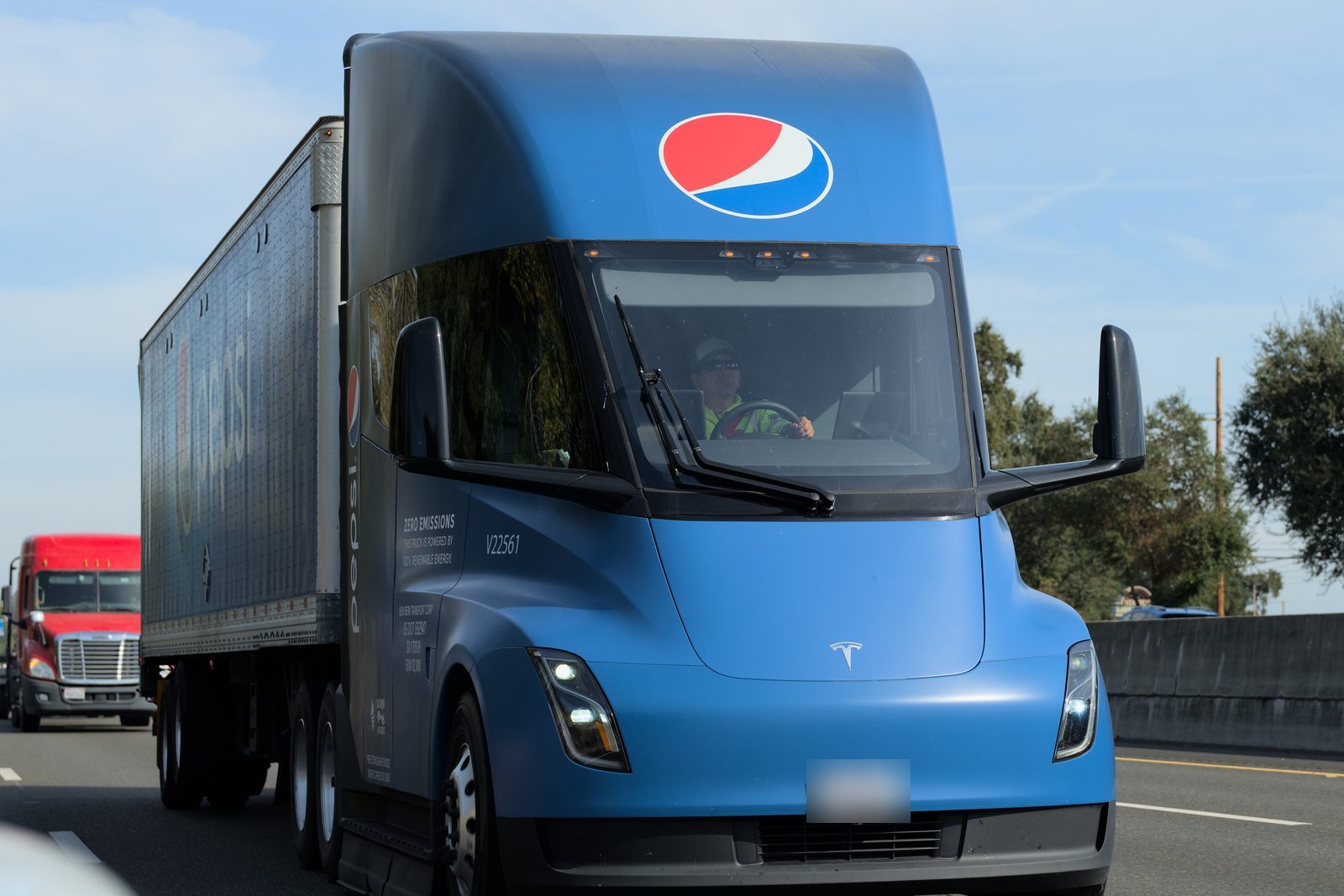 A blue Pepsi-liveried Tesla Semi truck driving on a California freeway